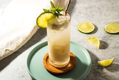 a tall glass filled with lemonade and lime on top of a blue saucer