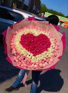 a person holding a bouquet of flowers in the shape of a heart