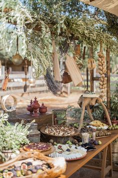 an outdoor market with lots of food on the table and hanging from the tree branches