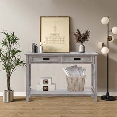 a grey console table with two drawers and a basket on top, next to a potted plant