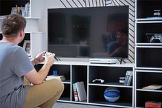 a man sitting in front of a tv holding a game controller