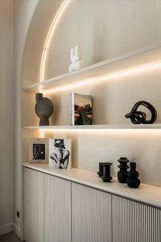 a white shelf with vases and other items on it's shelves in a room