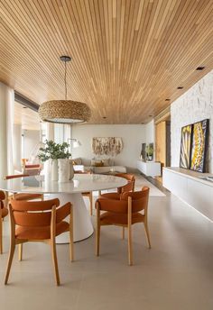 the dining room table is surrounded by orange chairs and an oval white table with wooden legs