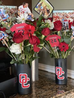 two vases filled with red and white flowers sitting on top of a marble counter