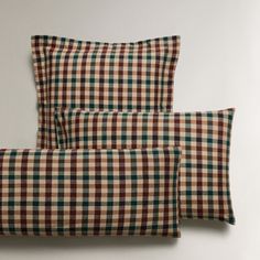 two brown and green checkered pillows sitting next to each other