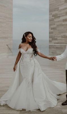 a bride and groom holding hands in front of the ocean at their wedding reception venue