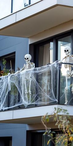 Two skeleton decorations with spider webs on a balcony. Diy Halloween Balcony Decorations, Diy House Halloween Decorations, Halloween Decorations For Apartments Balcony, Small Patio Halloween Decorating Ideas, Apartment Patio Halloween Decorating Ideas, Balcony Halloween Ideas Apartment, Apartment Patio Halloween Ideas, Halloween Apartment Patio Decor, Pumpkin Outdoor Decorating Ideas