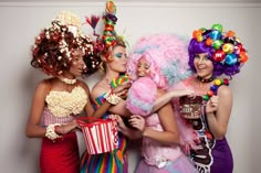 three women dressed up as clowns holding candy and popcorn