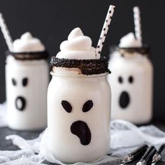 three mason jars decorated with white frosting and black sprinkles are on a table