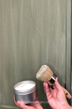 a person holding a brush and a can of paint in front of a door handle