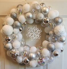 a wreath with silver and white ornaments hanging on the front door to decorate it for christmas