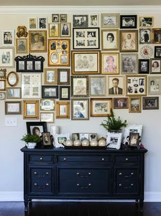 a wall full of framed pictures and photos on it's sideboard in a living room