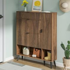 a wooden cabinet sitting in the corner of a room next to a potted plant