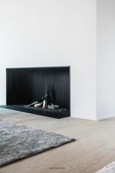 an empty room with a fireplace and rugs on the floor in front of it