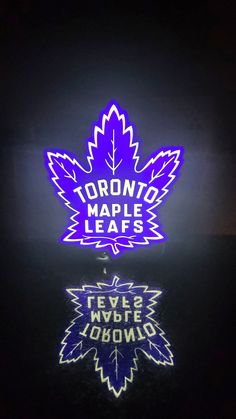 the toronto maple leafs neon sign is lit up in blue and purple colors on a black background