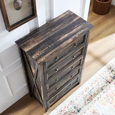 an old wooden chest of drawers on the floor in front of a painting and rug