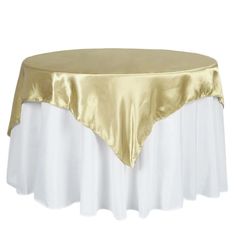 a gold and white table cloth on top of a round table with a satin overlay