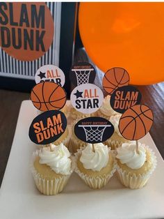 cupcakes with basketball decorations on them are sitting on a white plate next to an orange balloon