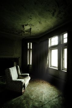 an empty living room with a couch and two windows in the dark, old house