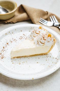 a white plate topped with a slice of pie next to a fork and bowl filled with powdered sugar