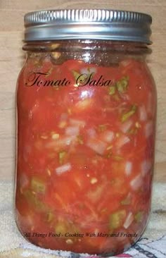 a jar filled with tomato sauce sitting on top of a table next to a towel