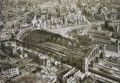 an old black and white photo of a train station in the middle of a city