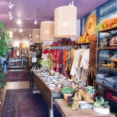 the inside of a clothing store with lots of items on tables and lamps hanging from the ceiling