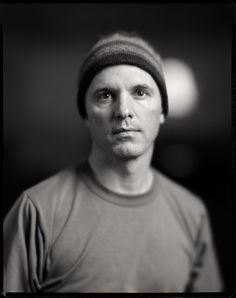 a black and white photo of a man with a beanie on looking at the camera