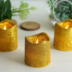 three gold glitter candles sitting next to each other