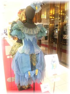 a blue dress with ruffles on display in front of a glass case at a store