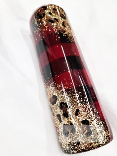 a red and black object with gold flecks on it's side, sitting on a white surface