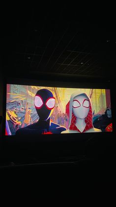 two animated characters on a large screen in a dark room