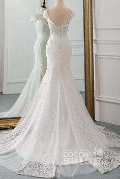 a white wedding dress is on display in front of a mirror and mannequins