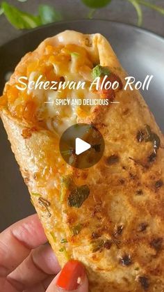 a hand holding a piece of food in it's left hand with the words sheezuan aloo roll on it