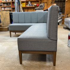 a gray couch sitting on top of a floor next to a book shelf filled with books