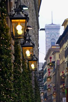 the street is lined with christmas lights and decorated trees in front of old stone buildings