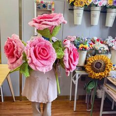 a person holding flowers in front of a wall with potted plants on it's sides