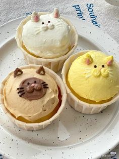 three cupcakes decorated to look like cats