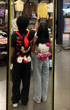 two children are standing in front of a mirror and looking at the clothing on display