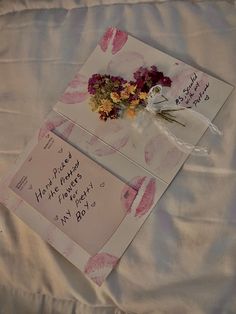 two greeting cards with flowers are on a bed