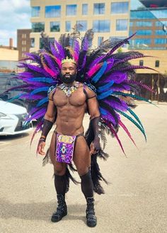 a man in an elaborate headdress and feathers is standing on the street with his hands behind his back