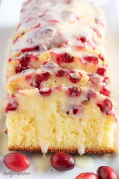 a close up of a cake on a plate with cherries around it and drizzled with icing