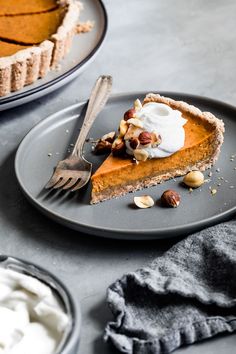 a slice of pumpkin pie on a plate with a fork and whipped cream in the background