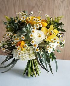 a bouquet of yellow and white flowers on a table