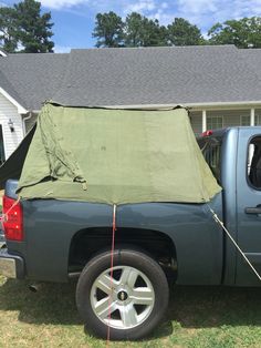 a pick up truck with a tarp on it's back in front of a house