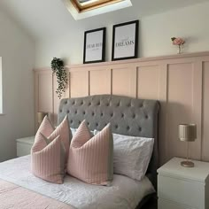 there is a bed with pink pillows and two pictures on the wall above it in this bedroom