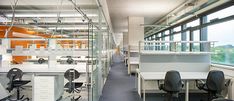 an office filled with desks and chairs next to large windows in front of them