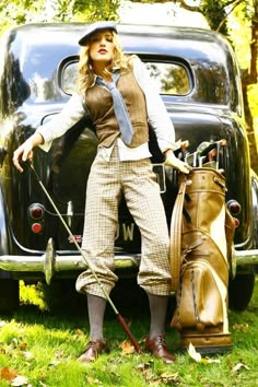 a woman standing in front of an old car holding a golf club and a bag