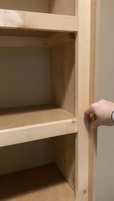 a person is holding the bottom half of a bookcase in order to open it