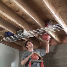 a man holding a basketball on top of a ladder